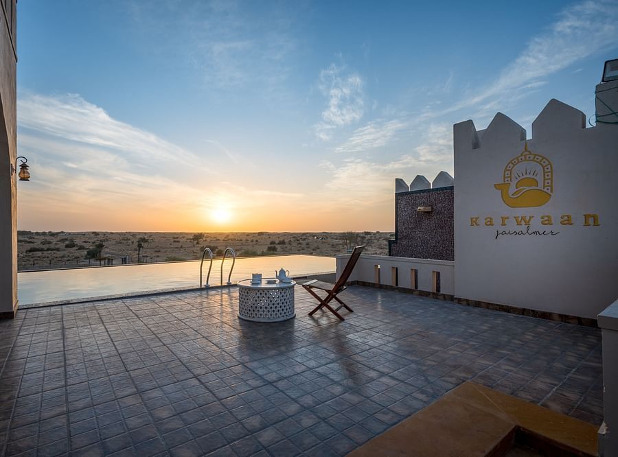 alt-text A foldable chair and a small table is placed near the pool - Karwaan Jaisalmer