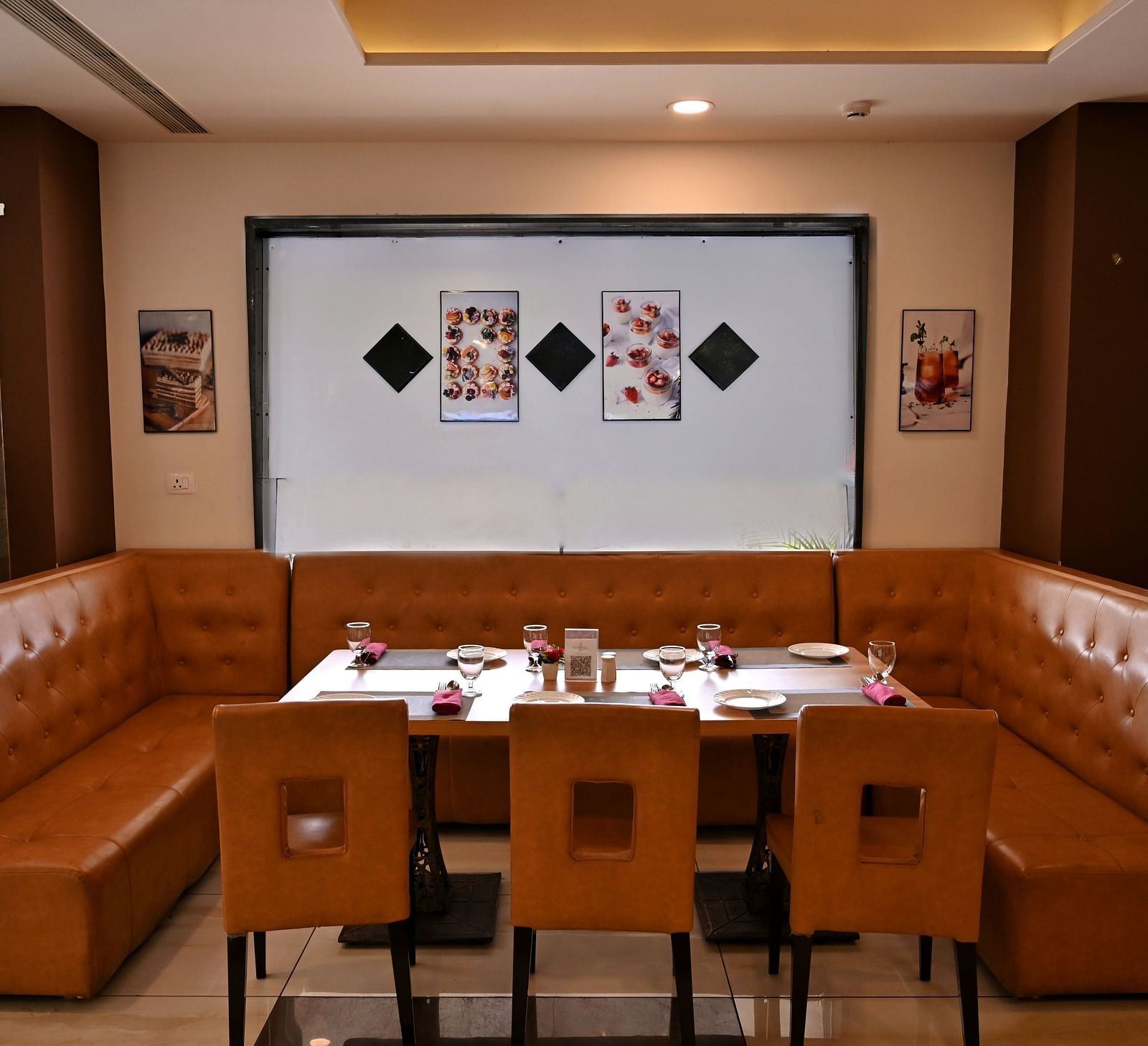 Cosy dining corner with a brown leather booth and wooden tables in a restaurant - TGI Insignia, Bhopal