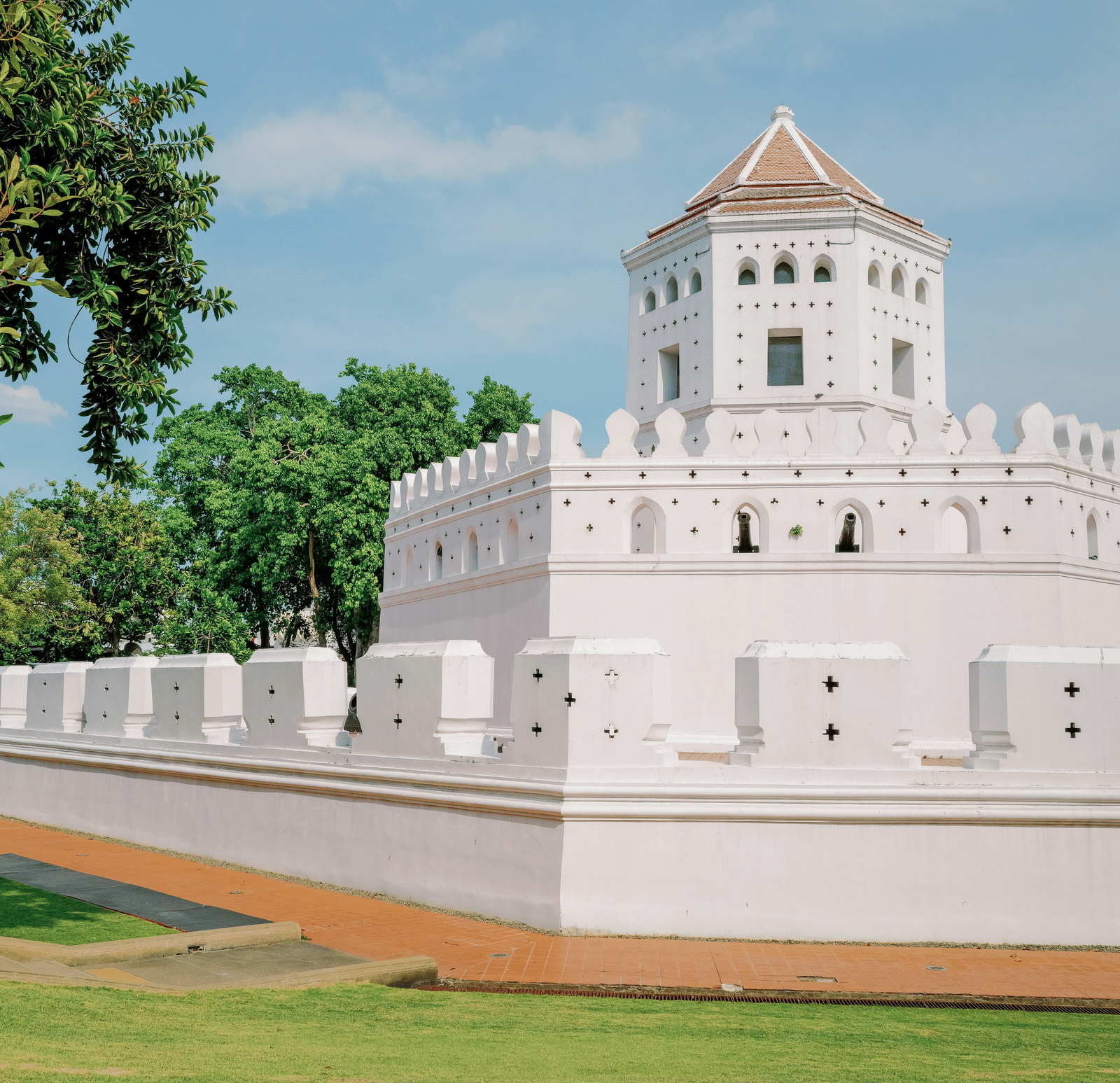 A white, multi-level fortress stands against a green background with a clear sky | French Architecture Pondy