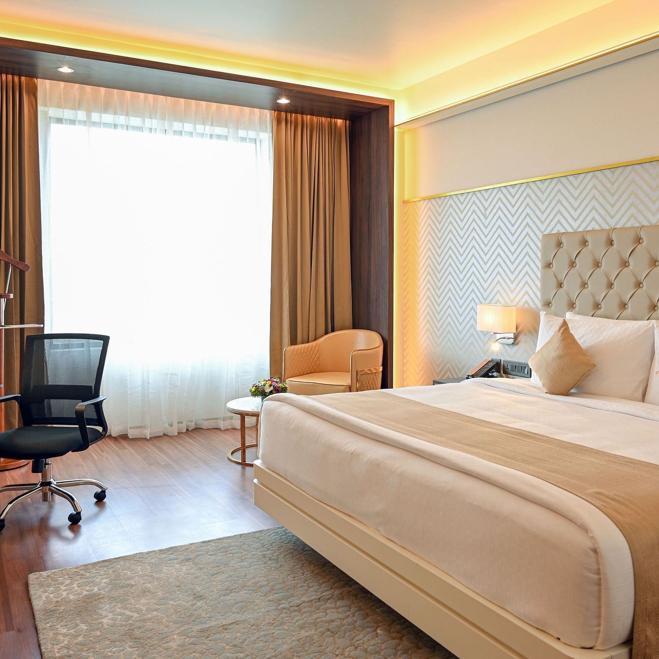 a king size bed and the work station at deluxe rooms in Calicut