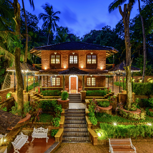 A far out view of Neemranas Three Waters facade with trees, steps and twilight sky in view for the perfect Cabo De Rama Stay.