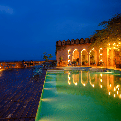 A vibrant blue pool with the resort at the background - Hill Fort Kesroli Alwar Rajasthan