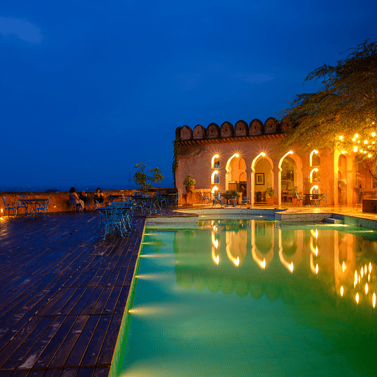A vibrant blue pool with the resort at the background - Hill Fort Kesroli Alwar Rajasthan