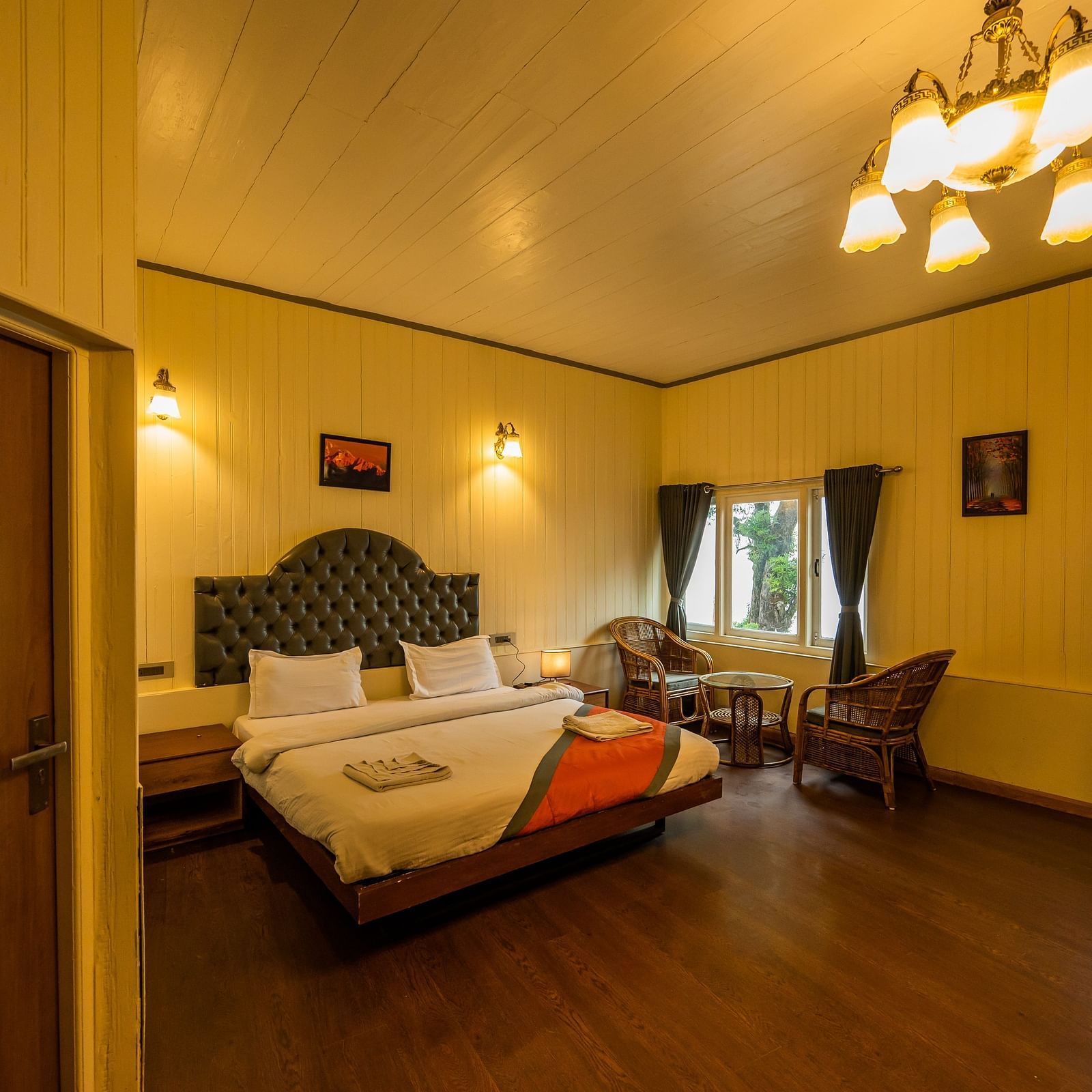 A room with beautiful interior with comfy bed, chair and bed side table at Arcadia Heritage Resort, Darjeeling 