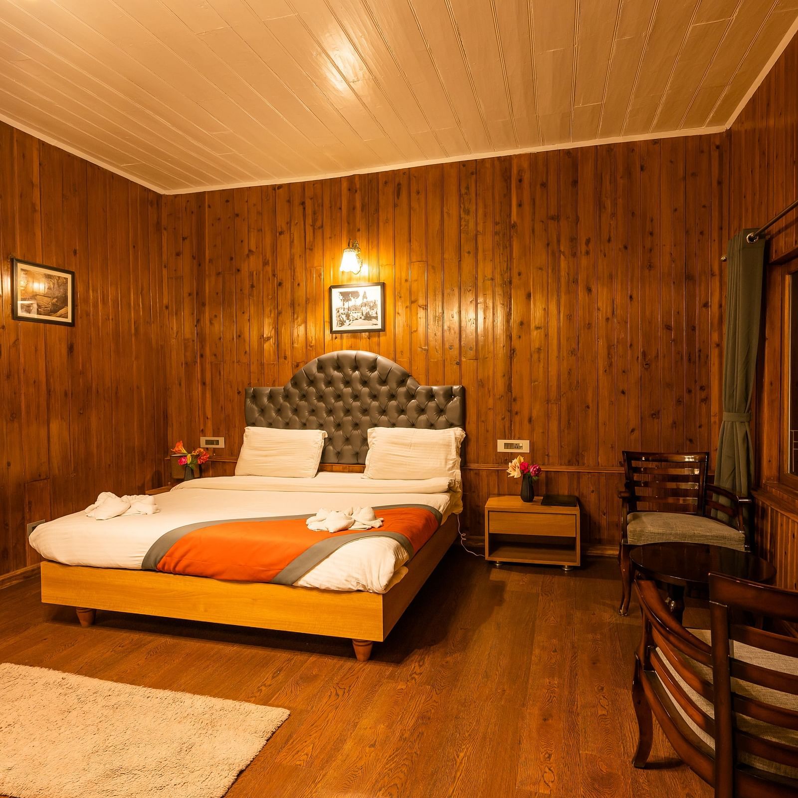 A spacious room with wooden furnished  comfy bed and the have bed side table and chair at Arcadia Heritage Resort, Darjeeling