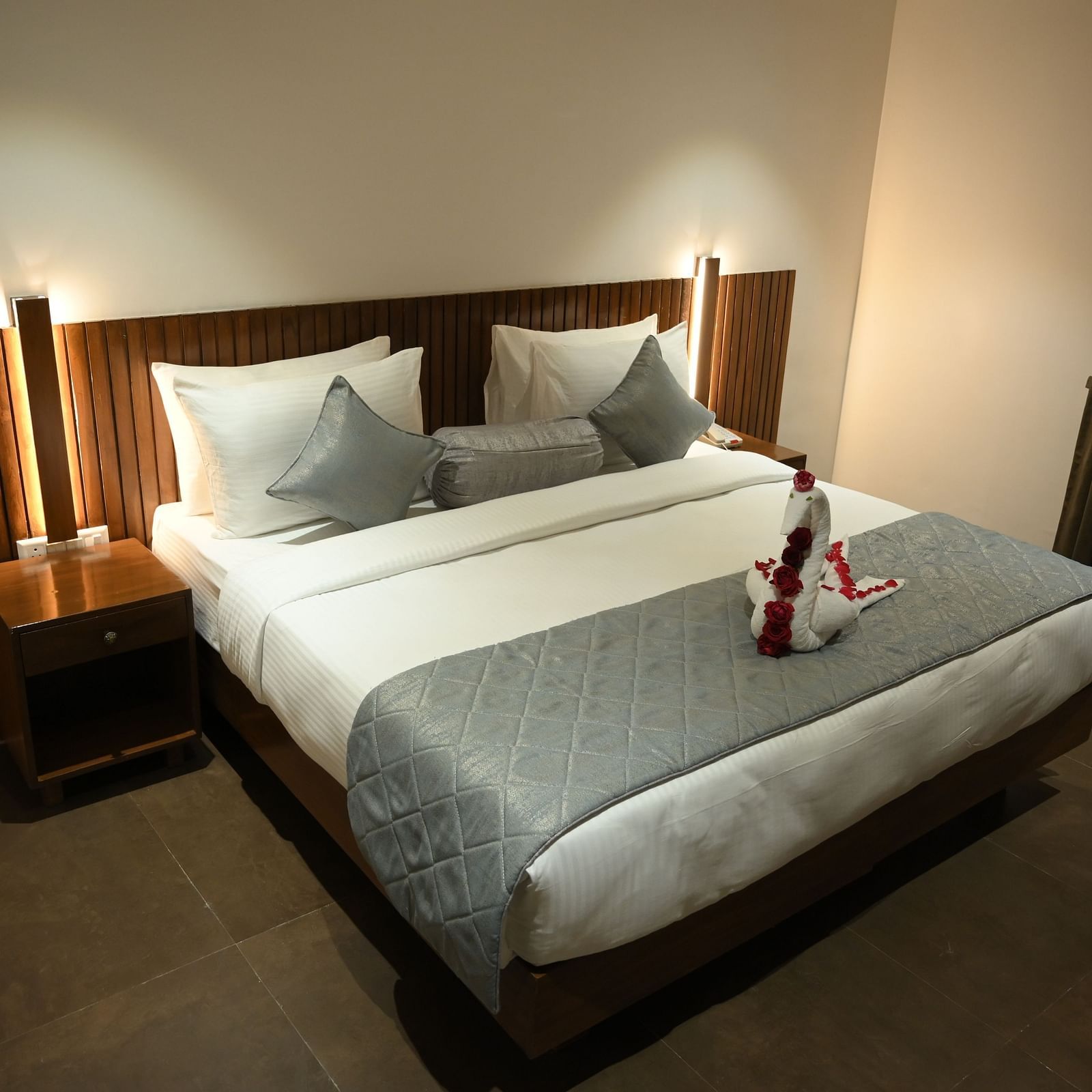 A doubled bed with a decorated towel at Deluxe room at  Mango Leaf Lake Resort, Pune