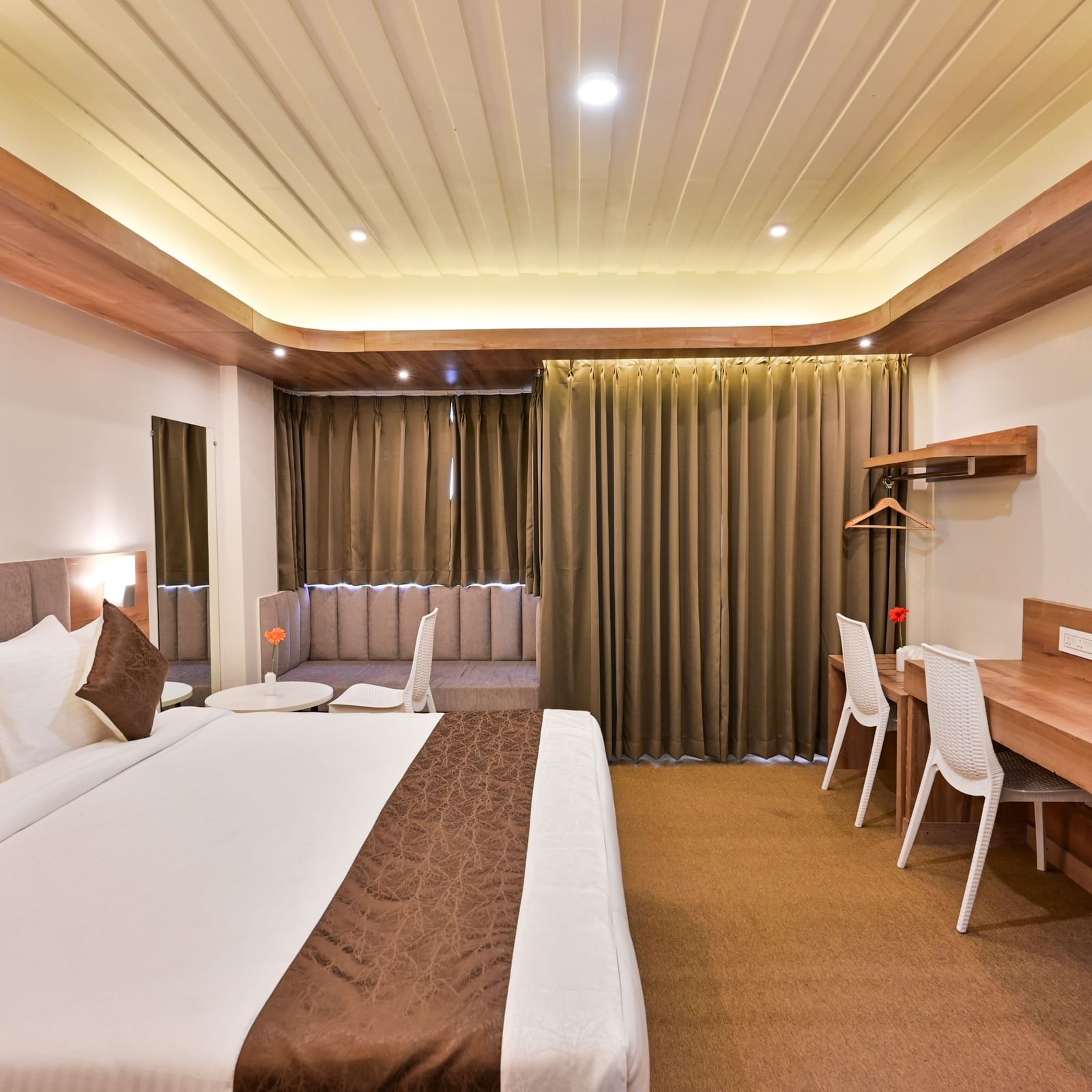 premium rooms with a sitting area and two white chairs at the soma hotel by avianna group, darjeeling