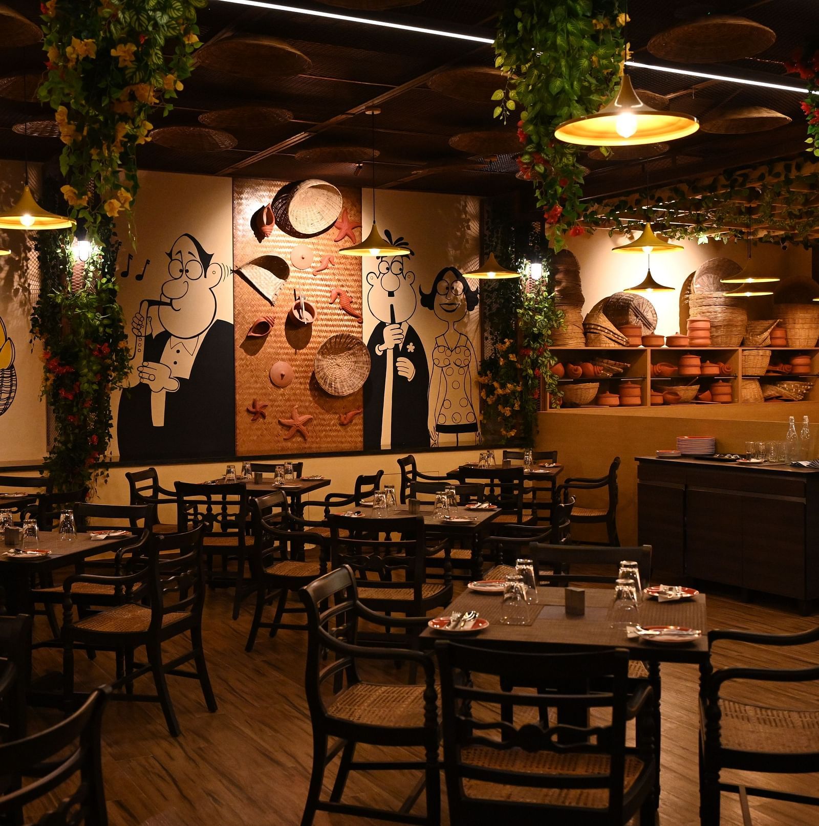 An image of a cafe with several sets of tables and chairs and the walls are  painted with doodles - Essentia Premier Hotel, Chennai.