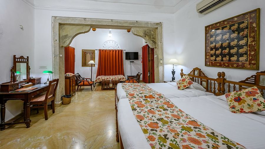 Deo Bagh - 17th Century, Gwalior - a spacious king size bed with floral pillows and bed runner on top of it at the Rohini Raja Mahal rooms in Gwalior 1