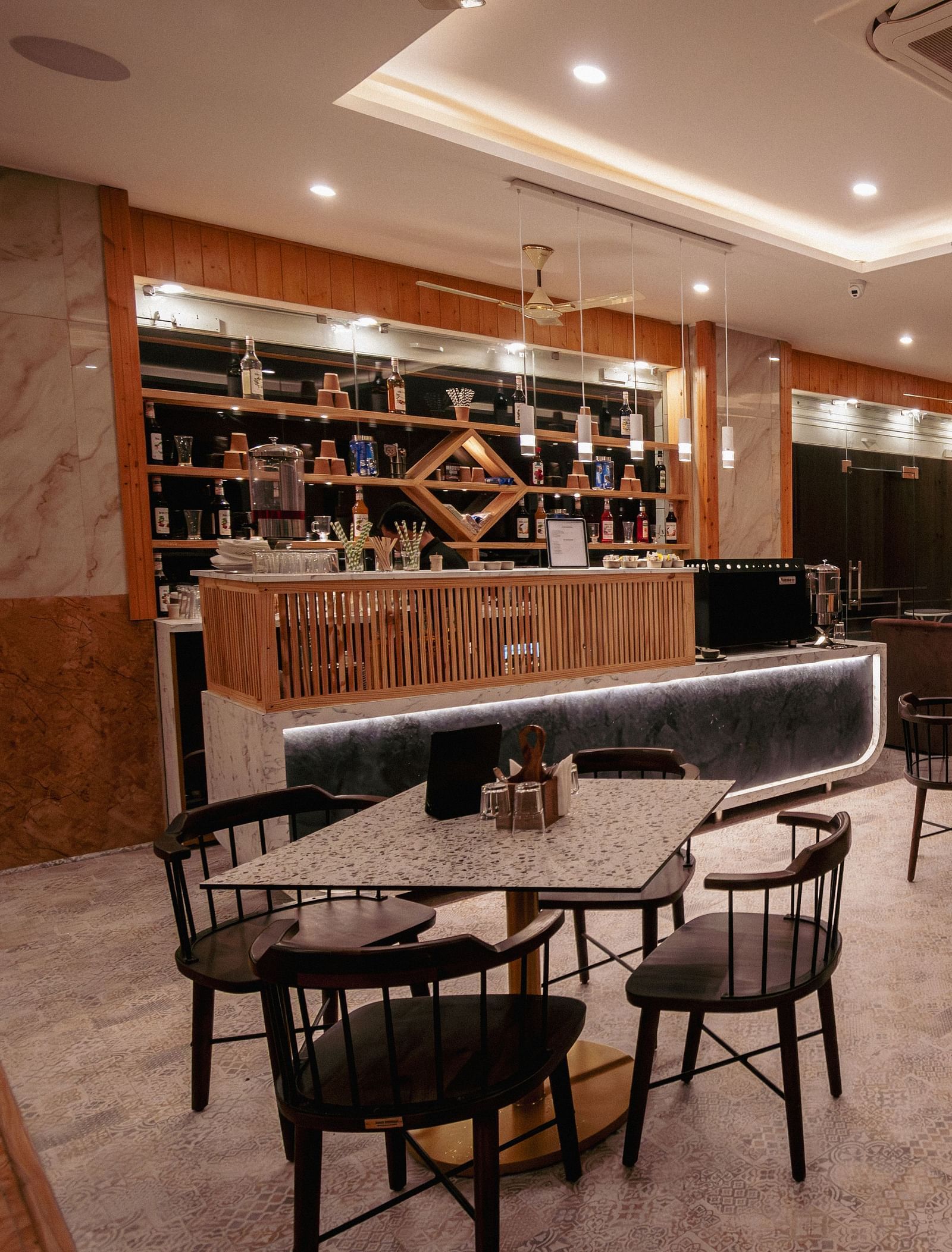 Image of the in-house restaurant featuring a fine dining setup, dim lights and a lady sitting on one of the chair | The Tattva Devprayag