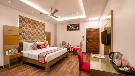 View of an Executive Room at Lords Inn Amritsar with a king bed, patterned headboard, wooden flooring, ceiling fan, and warm ambient lighting.