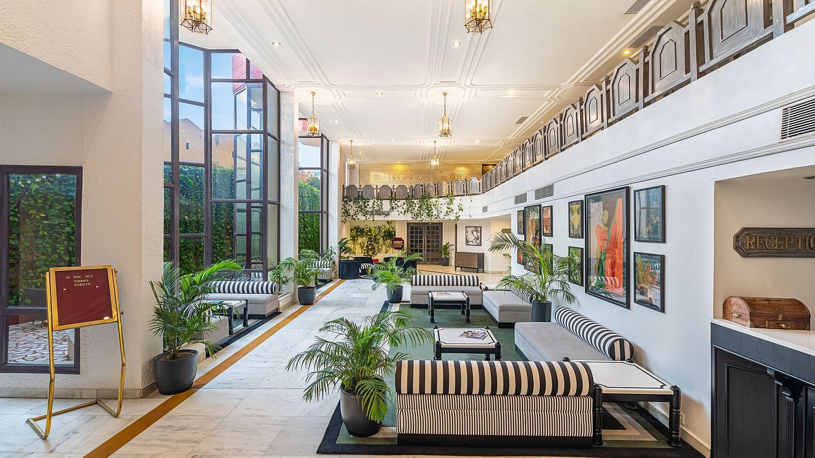black and white stripped sofas, wall decor, indoor plants and lighting in the lobby of Hotel Rajdarshan, Udaipur.