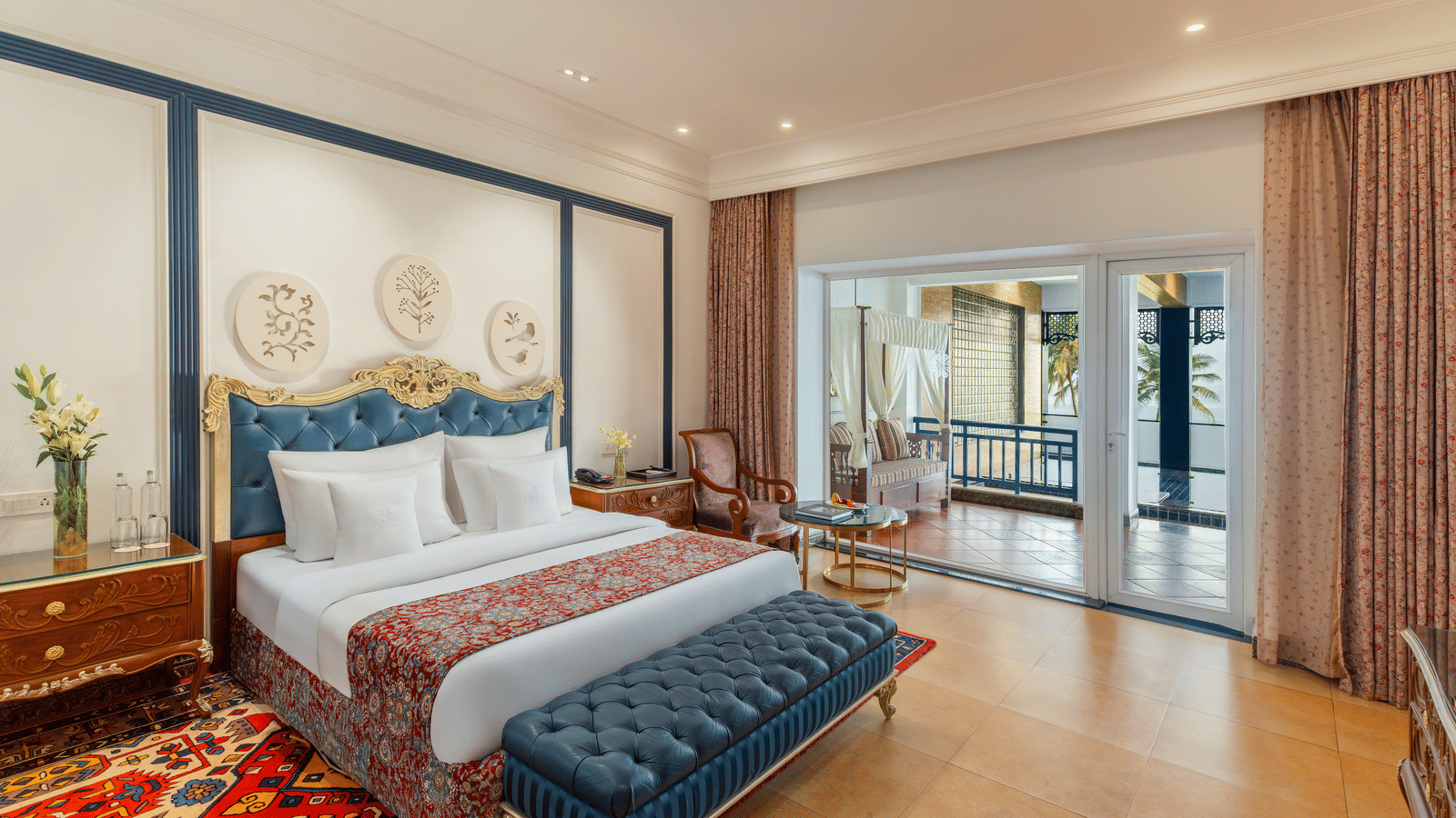 Room with a king bed, a tufted bench and sliding doors opening to a terrace with a daybed and sea beyond at MAYFAIR Palm Beach Resort, Gopalpur-on-Sea.