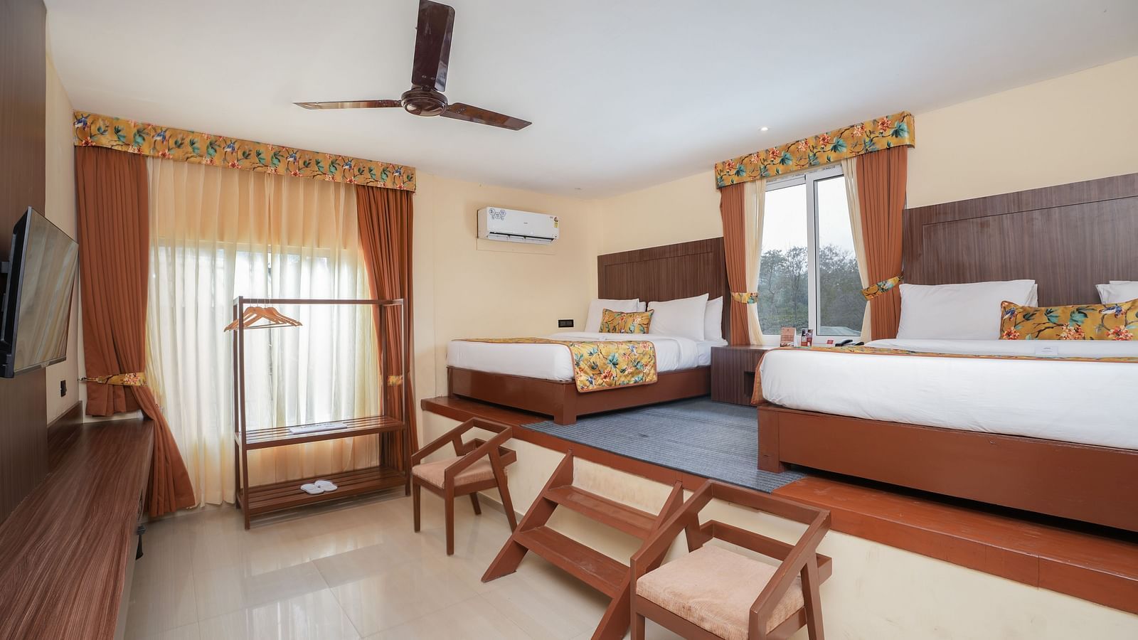 Family room with two large beds, wall-mounted television, and wooden furniture at Summit Green Lake Tea Resort & Spa, Kaziranga