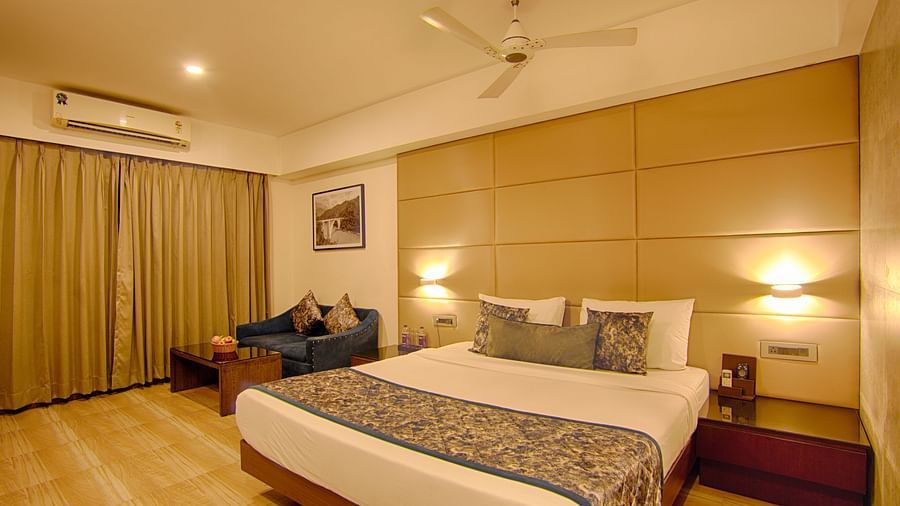 Cosy and modern room with double bed, seating area, and warm lighting at Voyage Milestone Hotel and Banquet Siliguri