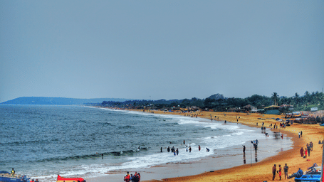 Wide view of a sandy Goa beach with people enjoying the shoreline and water sports along the Arabian Sea