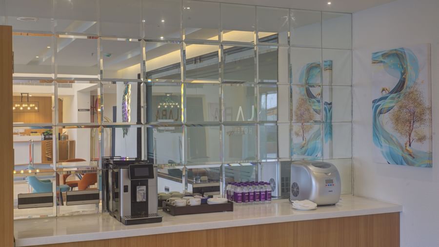A coffee maker along with several refreshments and packed drinking water kept on a counter at Ilara Hotels & Spa, Tada.