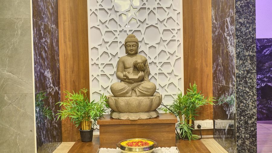 A stone statue of Lord Buddha with two green plants kept on both sides of it at Ilara Hotels & Spa, Tada.