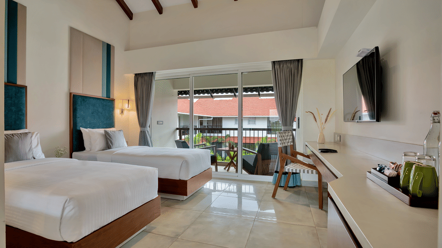 Twin Room at Mango Hill, Velankanni featuring 2 beds, a desk with a television, and a glass door opening to a balcony.