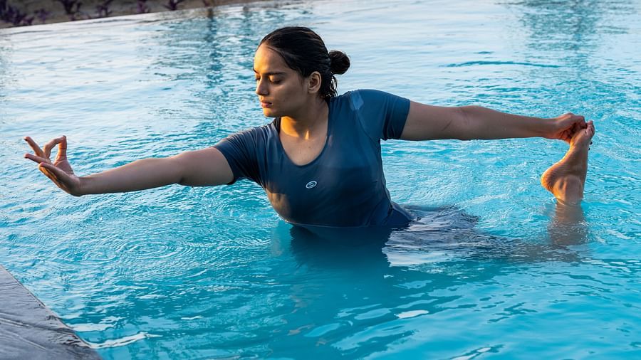 A woman preforming a yoga asan in our outdoor pool - Rajbagh Wellness, Udaipur