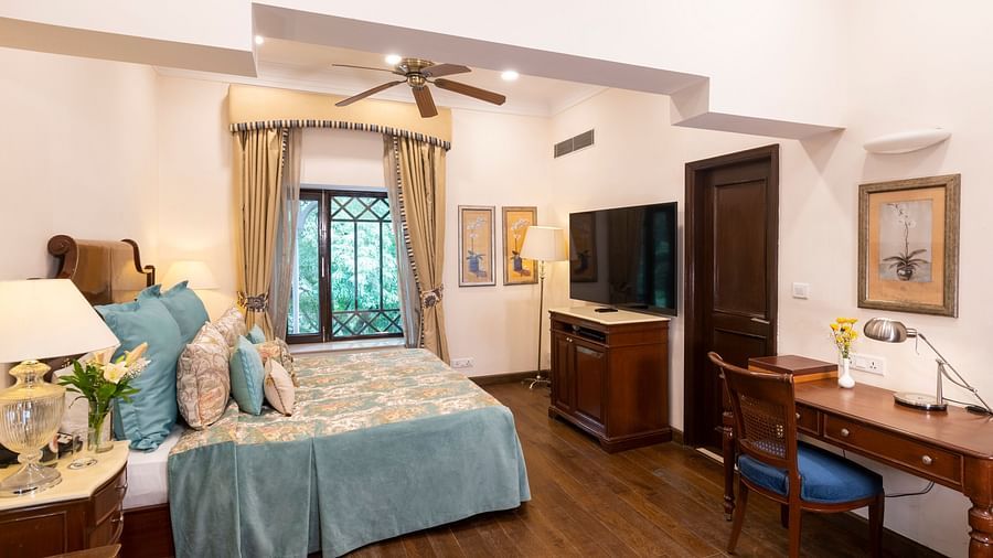 full view of the deluxe room with wooden interiors and a window at the far end at The Claridges Nabha Residence