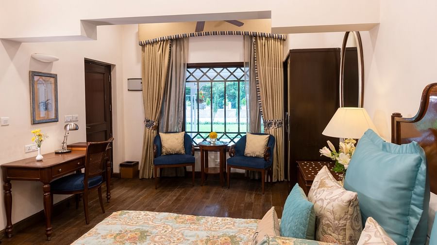 image of the deluxe room with a bed and a seating area on the other side at The Claridges Nabha Residence