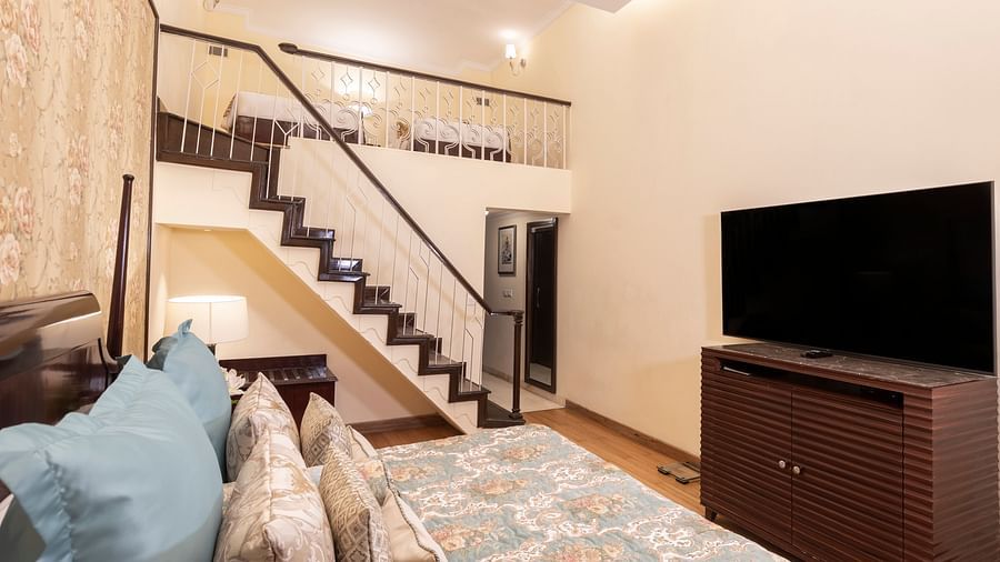 image of a king size bed with the staircase leading to the first floor of the suite at The Claridges Nabha Residence