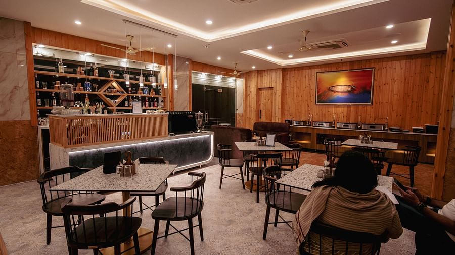 Image of the in-house restaurant featuring a fine dining setup, dim lights and a lady sitting on one of the chair | The Tattva Devprayag
