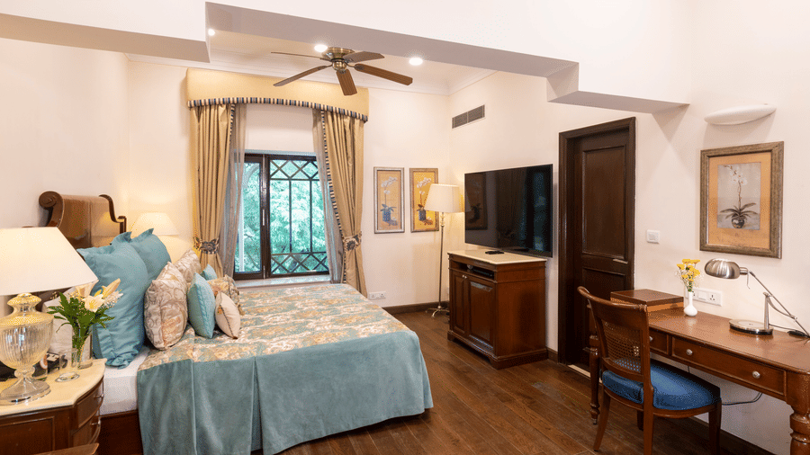 full view of the deluxe room with wooden interiors and a window at the far end at The Claridges Nabha Residence