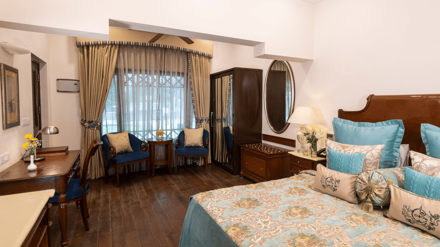 full view image of the Deluxe room with the bed and the searing area in direct view at The Claridges Nabha Residence