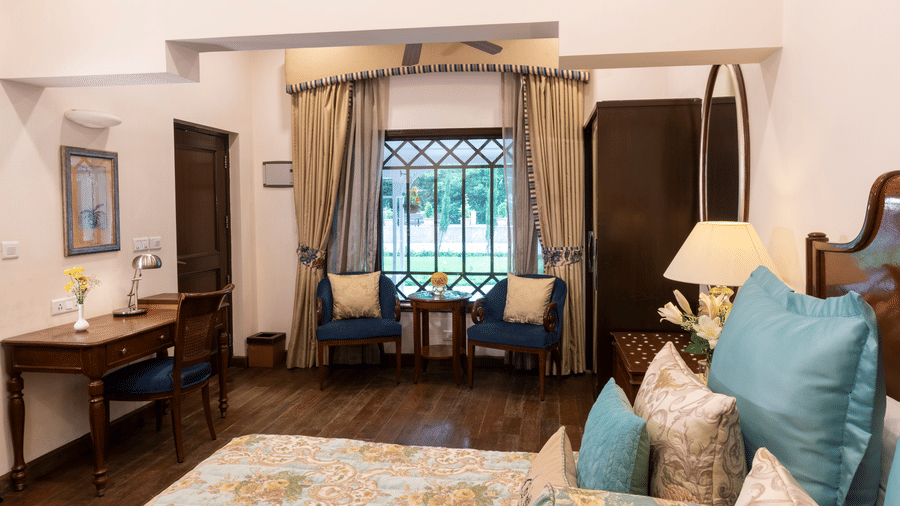 image of the deluxe room with a bed and a seating area on the other side at The Claridges Nabha Residence
