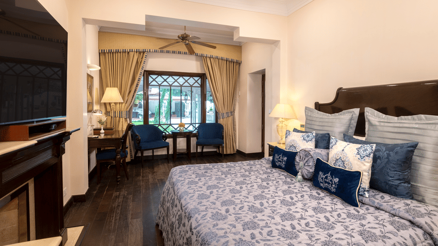 image of a king size bed and the seating area of the Claridges room at The Claridges Nabha Residence