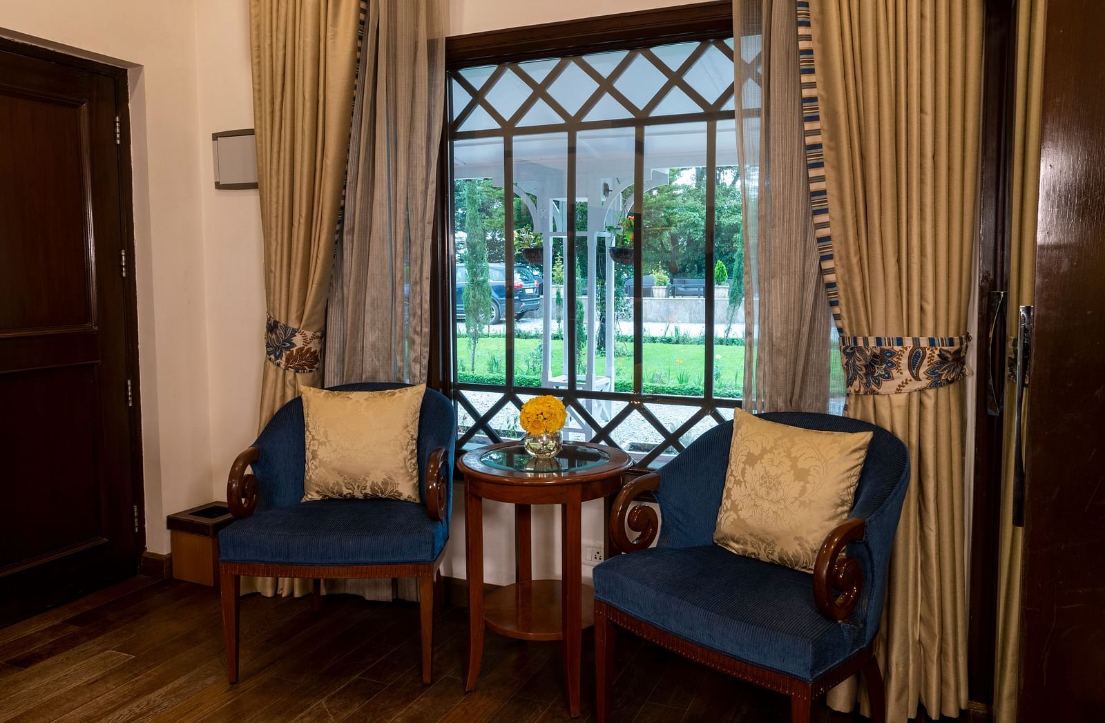 image of the seating area with teal cushioned chairs at the Deluxe Room at The Claridges Nabha Residence
