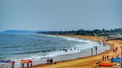 An image of a beach where people are seen roaming around with surfboards