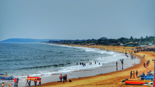 An image of a beach where people are seen roaming around with surfboards
