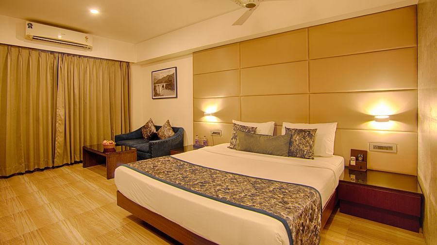 Cosy and modern room with double bed, seating area, and warm lighting at Voyage Milestone Hotel and Banquet Siliguri