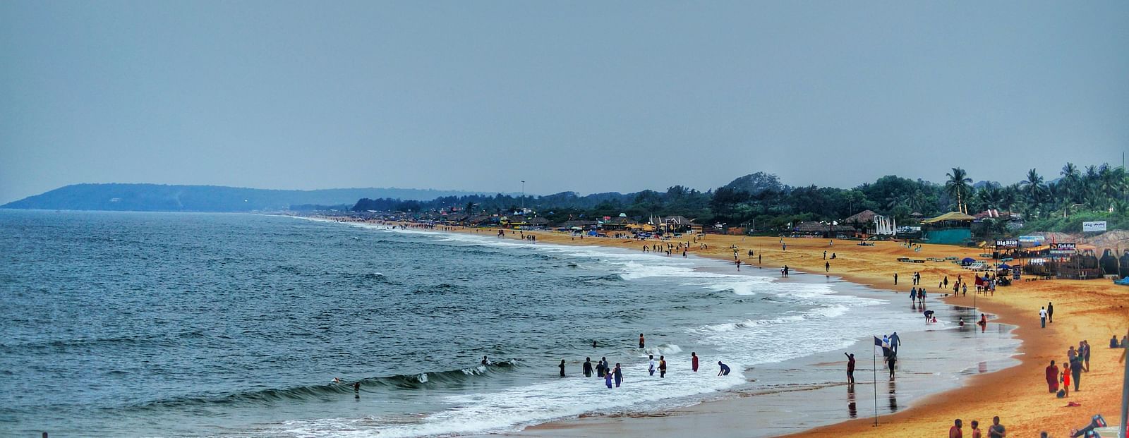 Sea beach under clear sky during daylight with people chilling on the shore