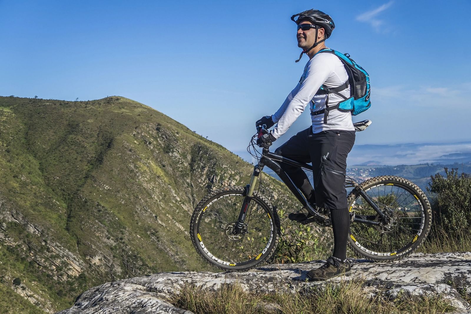 Man cycling uphill on a dirt trail, scenic mountain view, adventure and fitness.