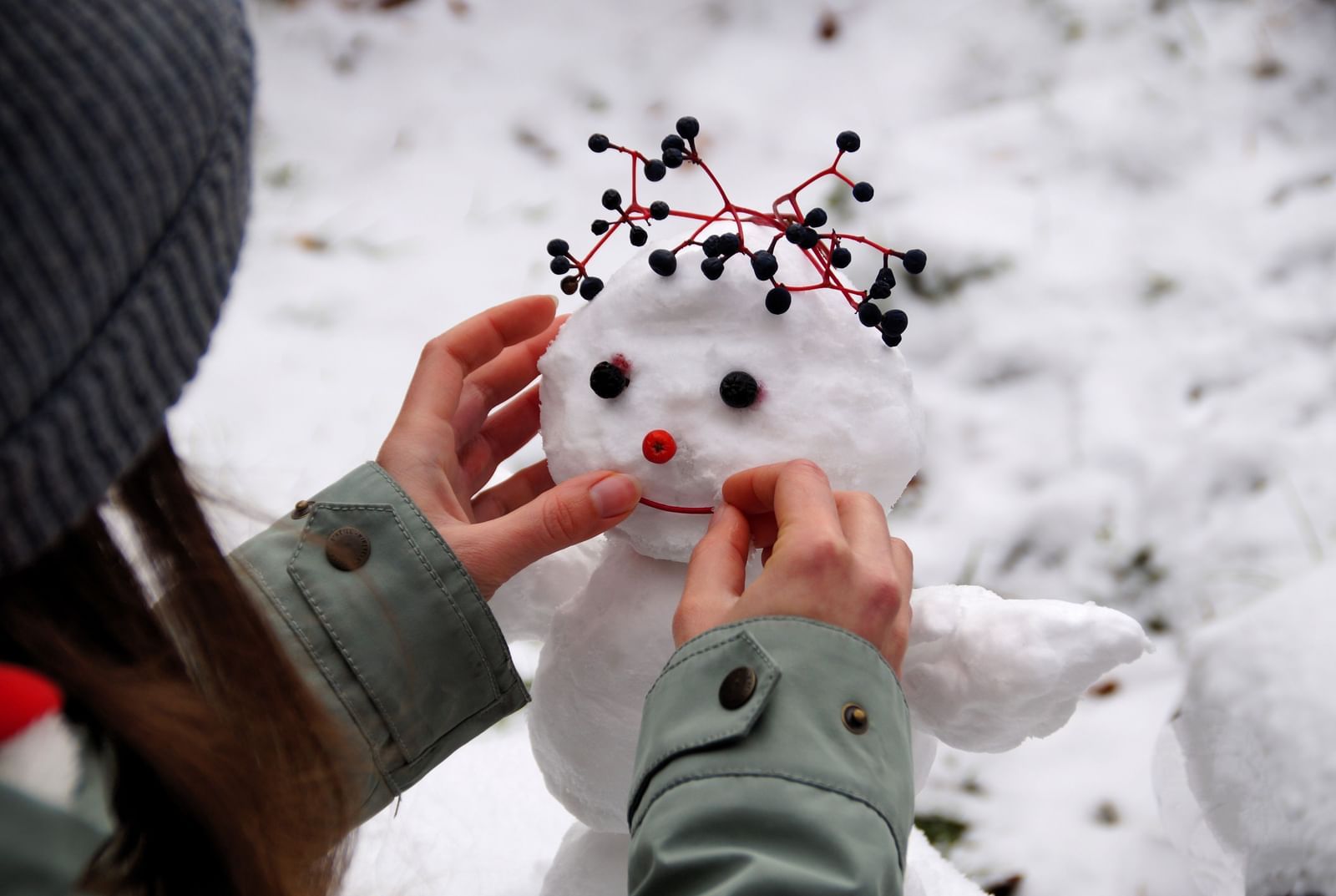 A small child making a snow man near a snow filled ground - one of the Exciting Things to Do in Mumbai