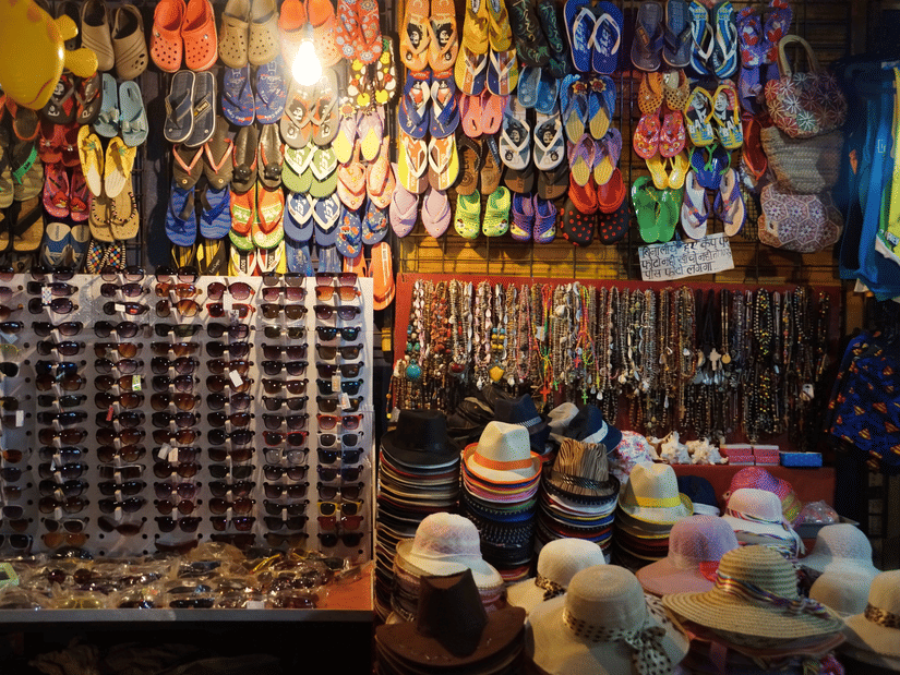 Vibrant street market shop in Goa with sandals, sunglasses, hats, and accessories.