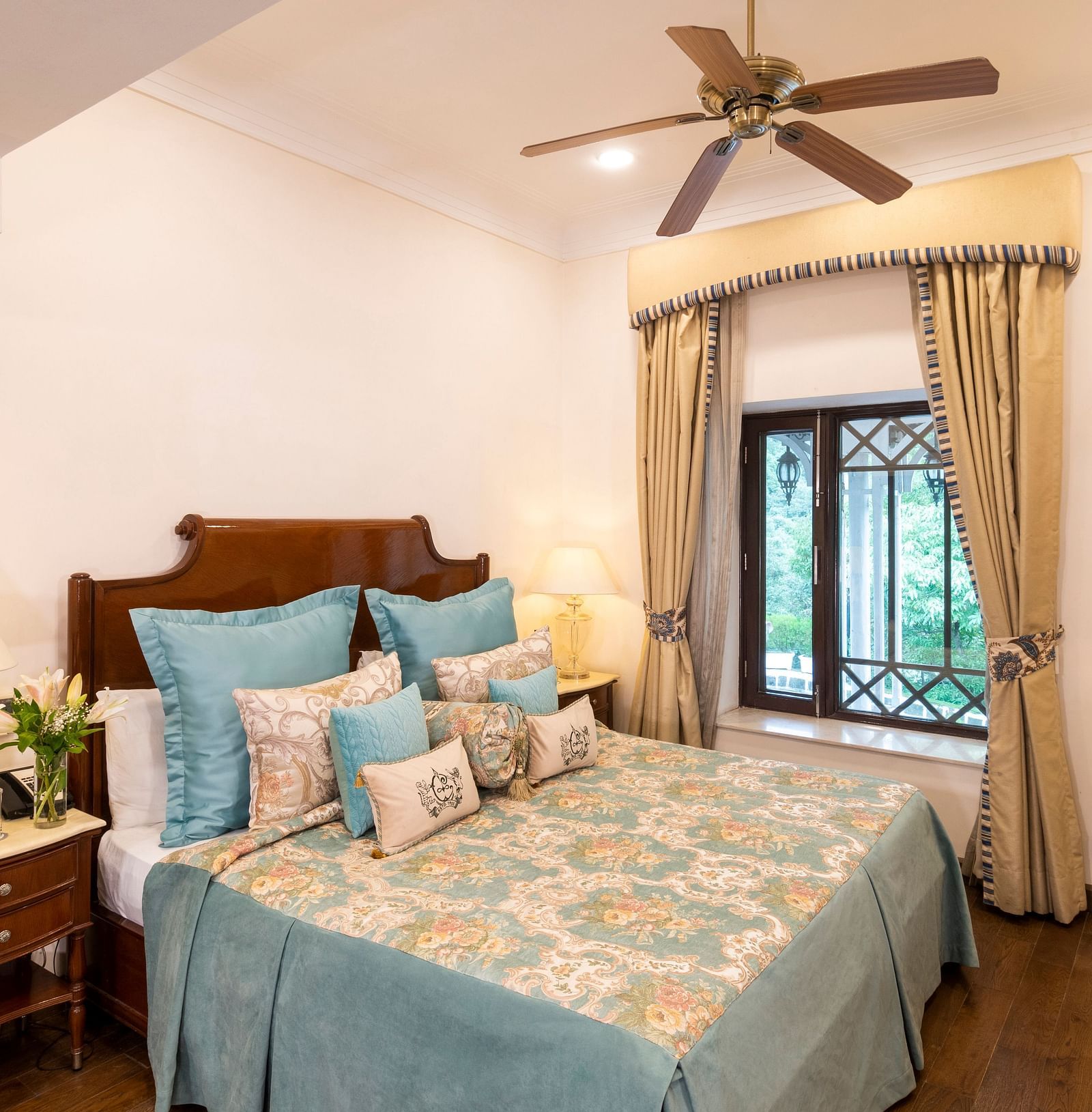 image of the king size bed with sky blue coloured sheets and the window view at the Deluxe Rooms at The Claridges Nabha Residence