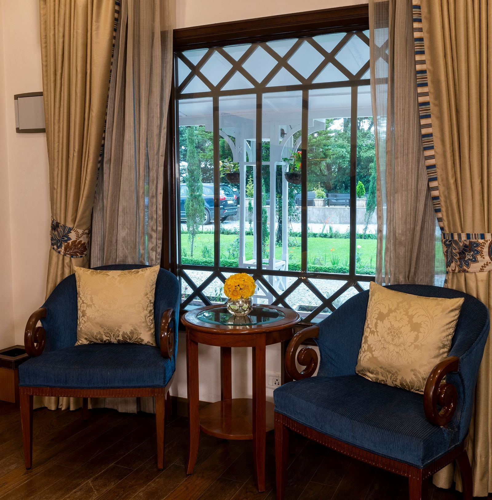 image of the seating area with teal cushioned chairs at the Deluxe Room at The Claridges Nabha Residence