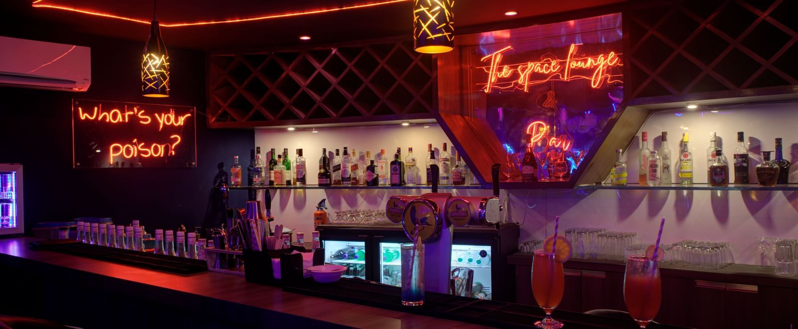 Stylish bar counter with colourful lighting and illuminated drink display at Ilara Hotels & Spa, OMR, Chennai