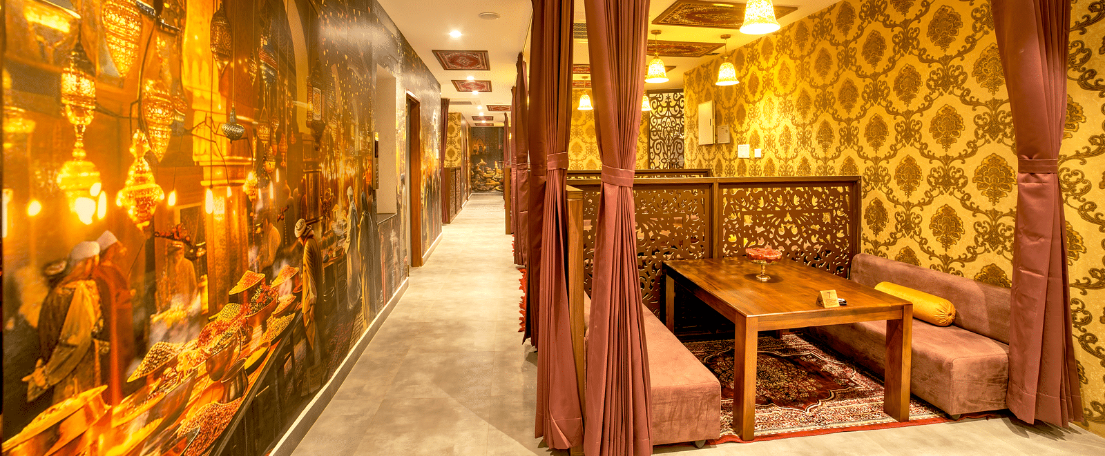 Themed restaurant with golden lighting, plush seating, and ornate décor elements at Ilara Hotels & Spa, OMR, Chennai