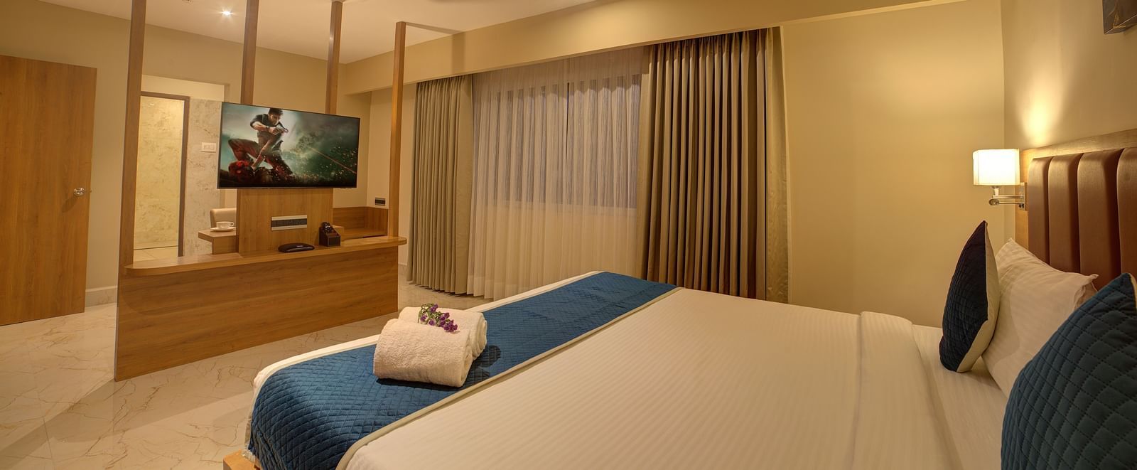 A wide angle shot of the bedroom at Ilara Hotels & Spa, Tada at the Executive Suite with a plush double bed and a flat screen television in front of it.