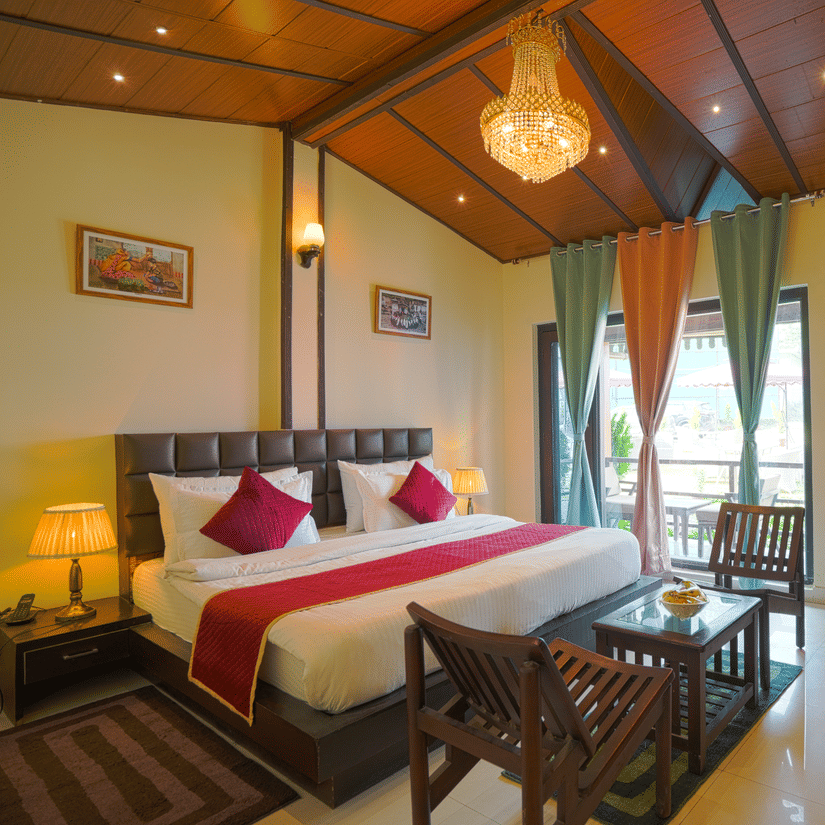 A neatly arranged room with a big bed, 2 wooden chairs on either side of a coffee table, a chandelier and full length curtains | Sol Glow Resort, Nainital
