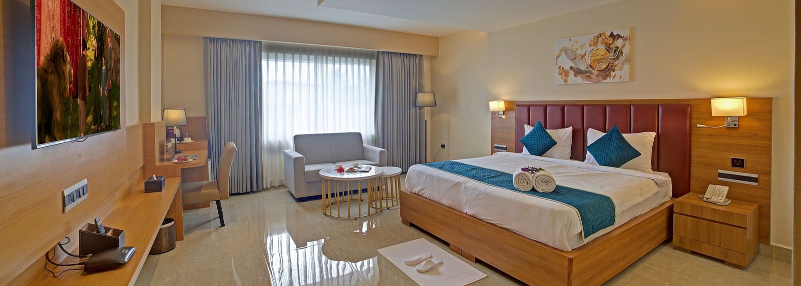 A brightly lit bedroom at the Junior Suite at Ilara Hotels & Spa, Tada with a double bed along with a bed side tables besides it.