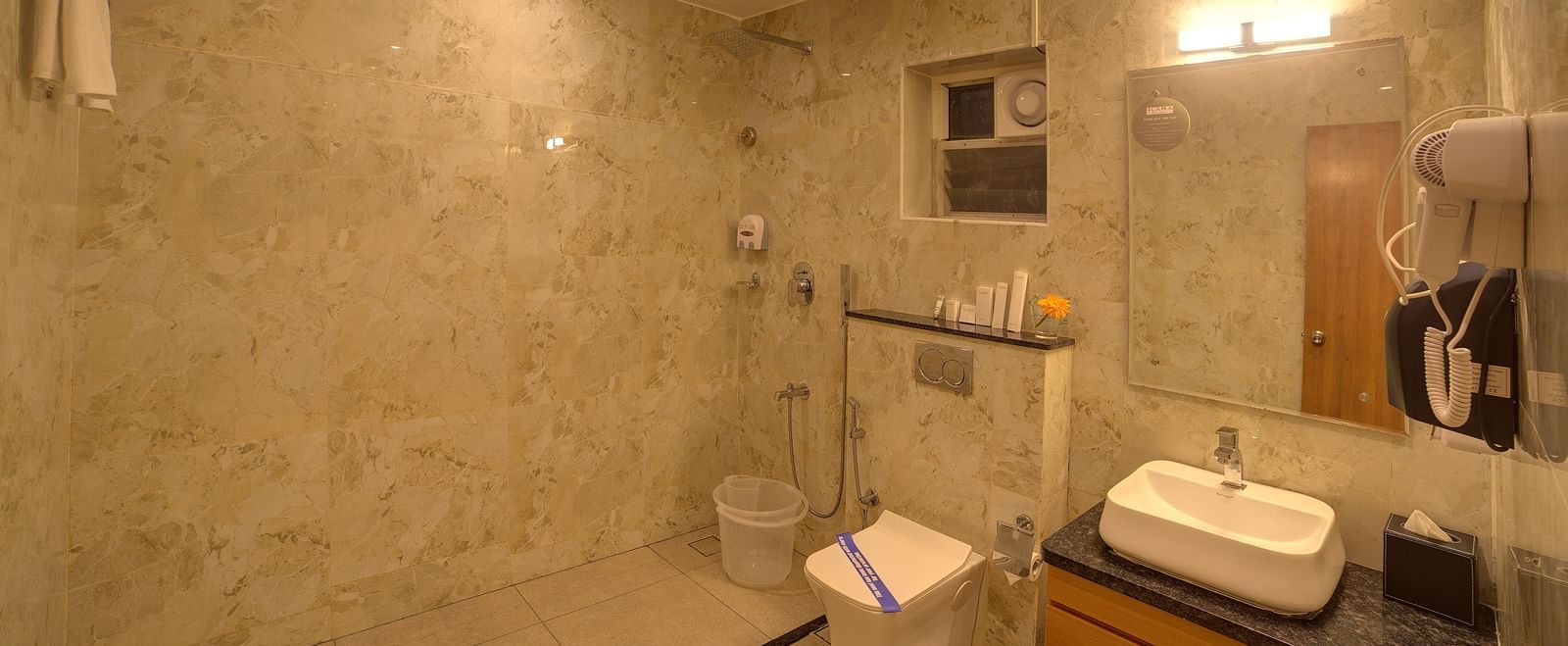 A bathroom with a wash basin and a vanity area in the corner at Ilara Hotels & Spa, Tada.
