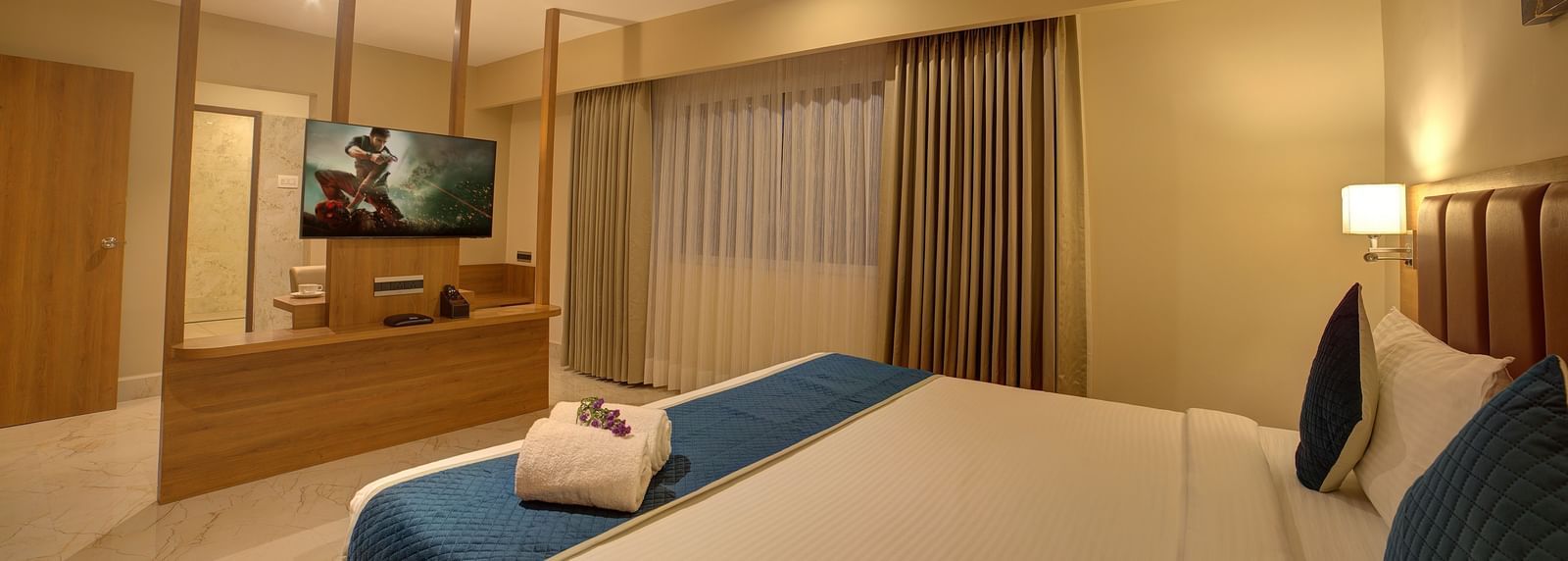 A wide angle shot of the bedroom at Ilara Hotels & Spa, Tada at the Executive Suite with a plush double bed and a flat screen television in front of it.