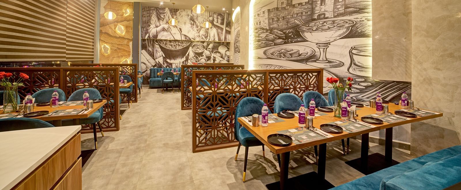 Restaurant booth seating with classic artwork on the walls at Ilara Hotels & Spa, OMR, Chennai